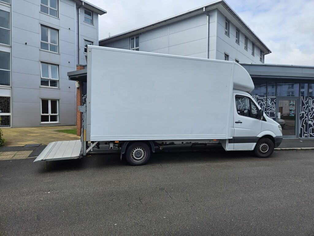 Merit Removals van navigating the streets of Manchester, packed with household goods for a move.